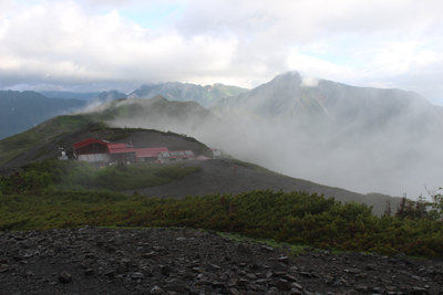 蝶ヶ岳山頂から見た蝶ヶ岳ヒュッテと常念岳、大天井岳方面の写真