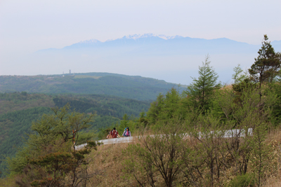 中央アルプスを背に舗装道路を歩いて鉢伏山に向かっている写真