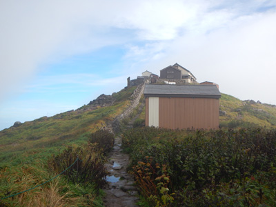 月山頂上小屋から見た山頂の月山神社本宮の写真