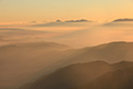 朝日に色づいたベールのような雲海の上に浮かぶ剣岳方面の写真にリンク