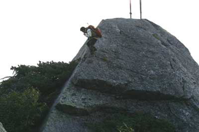 剣の立つ岩の裏側を下りてくる人の写真
