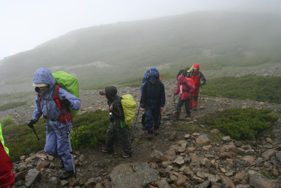 霧に包まれた稜線を歩くメンバーの写真