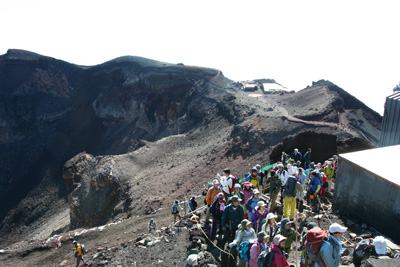 剣ヶ峰の標識の前で写真を撮る順番待ちをしている人たちの写真