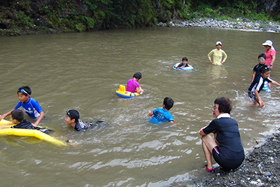 川に入って浮き輪などで遊ぶ子どもたちの写真