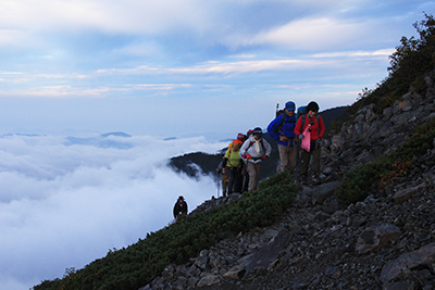 雲海から頭を出した光岳方面を背に小聖岳直下を登っている写真