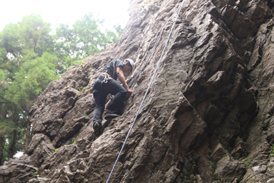 男岩南面のフェースを登るKMさんの写真