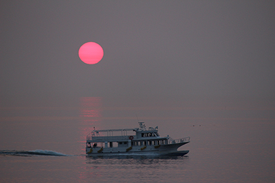 真っ赤な夕日と通過する船の写真